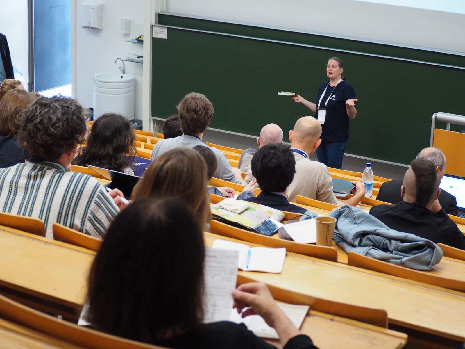A speaker presenting at the blackboard to a full hall at TUC 2026