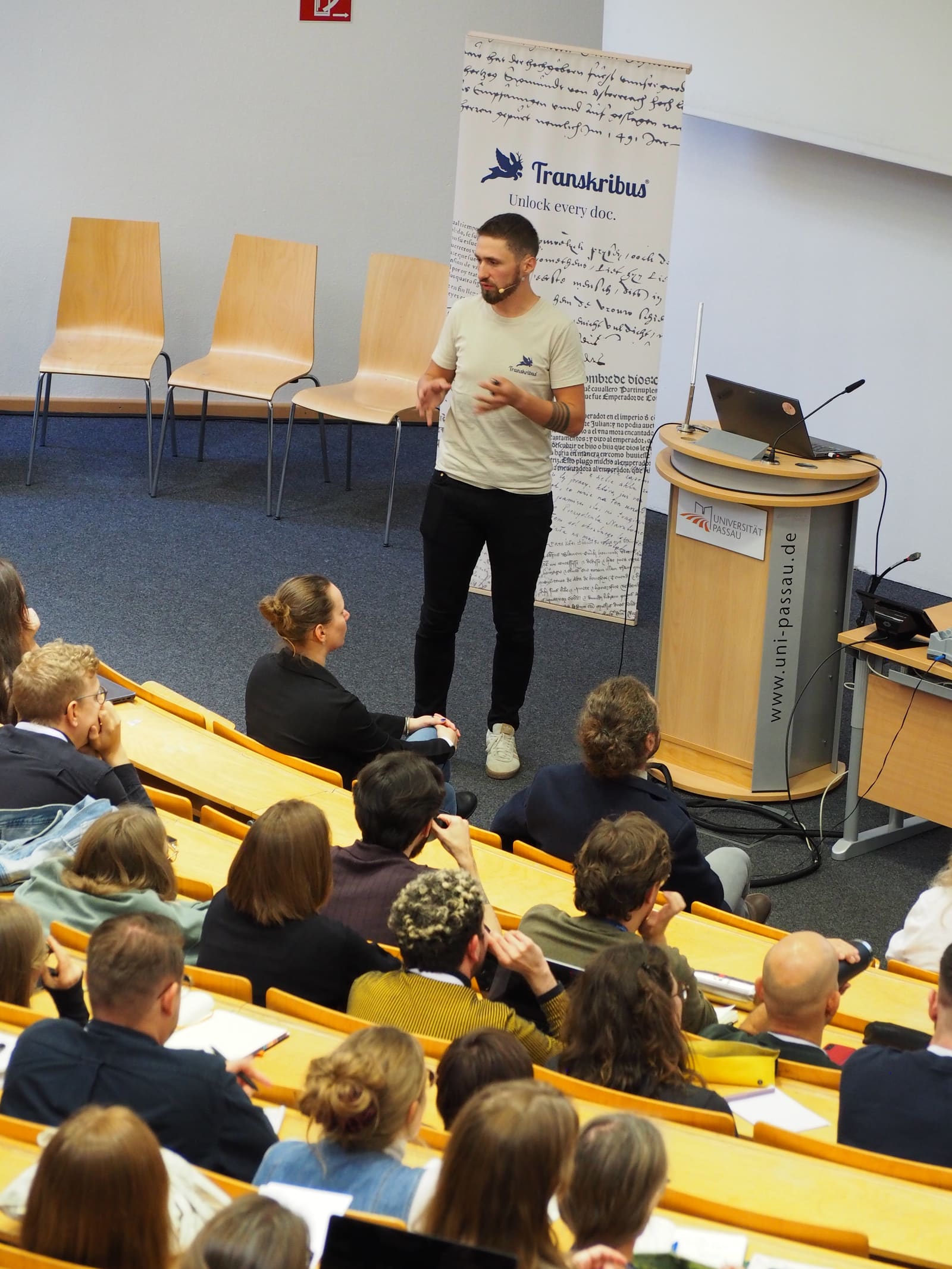 A speaker presenting to a full lecture hall at TUC 2026